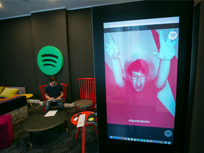 A Spotify Ltd. logo sits on display as an employee uses a laptop computer in a work area inside the music streaming company's offices in Berlin, Germany