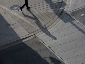 The shadow of a commuter is cast on the pavement in the financial district of Toronto. The launch of operations for a Canadian national securities regulator, a project long stymied by political bickering, has been delayed until 2018.