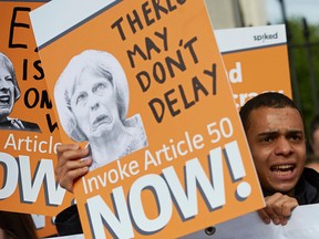 Pro-Brexit supporters holds up placards as they demonstrate outside Downing street in London.