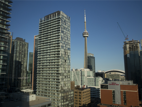 The CN Tower, centre, stands behind residential and commercial buildings in the financial district of Toronto.