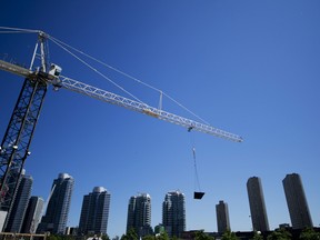 A crane moves a dumpster past a cluster of condo towers as construction takes place