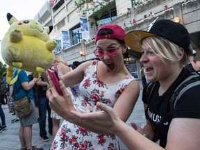 Sara Zarya, left,  and Sam Engstrom play Pokemon Go with at the base of the CN Tower in Toronto.