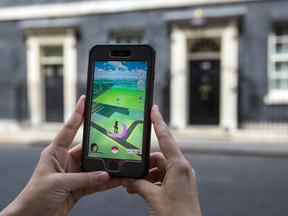 A woman poses for a photograph with Pokemenon Go game on her phone in Downing Street on July 14, 2016 in London, England