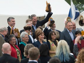 Premiers hold up moccasins after being gifted them by indigenous elders during a meeting of Premiers in Whitehorse, Yukon