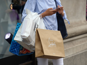 A shopper checks her mobile phone while holding shopping bags