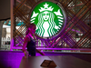 A woman walks by the logo of Starbucks  at its first shop in South Africa and Sub Saharian africa