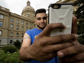 Simrit Birdi plays Pokemon Go on his cellphone at the Alberta Legislature grounds, in Edmonton.