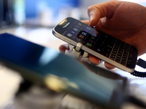 An employee holds a BlackBerry Ltd. Classic smartphone at a store in Waterloo, Ontario.