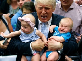 Republican presidential candidate Donald Trump holds children during a campaign rally.