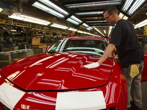 A worker checks the paint on a Camaro at the GM factory in Oshawa, Ont.