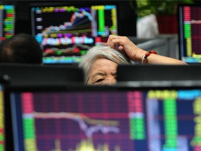 A woman monitors stock prices at a brokerage house in Jiujiang city in central China's Jiangxi province