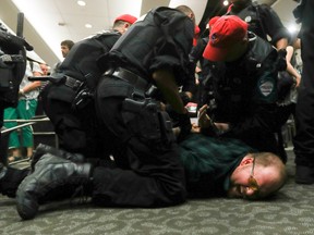 A protester is subdued in  the hearing room where Montreal mayor Denis Coderre was scheduled to speak at the National Energy Board public hearings into the Energy East pipeline project.