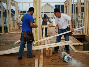 Contractors work on the wood framing for a house