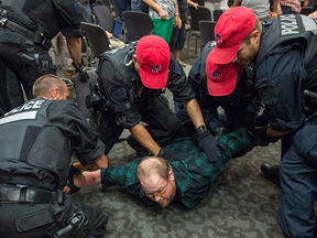 A demonstrator is arrested after disrupting the National Energy Board public hearing into the proposed Energy East pipeline.