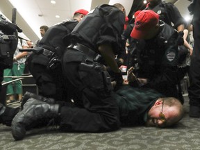 A protester is subdued in  the room where National Energy Board public hearings into the Energy East pipeline project where scheduled to start in Montreal in August. The hearings, however, were cancelled.