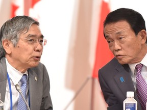 Japanese Finance Minister Taro Aso (R) talks with Governor of the Bank of Japan Haruhiko Kuroda (L)