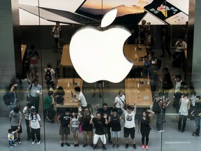 Customers pose for a photograph at Apple Inc.'s Canton Road store in the Tsim Sha Tsui district of Hong Kong, China.