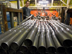 Derrick Barber grabs steel pipes that have been perforated before they are welded into a section of a bumper at Formet in St. Thomas, a Magna company that builds truck frames, bumpers for all 3 of the major manufacturers.