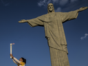 Maria Isabel Barroso, former Brazilian volleyball champion, holds the lit Olympic torch in front of the Christ the Redeemer statue in Rio de Janeiro.