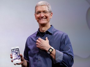 Apple CEO Tim Cook, holding an iPhone 6 Plus and wearing an Apple Watch