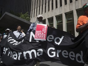Demonstrators hold up signs during a protest outside the offices of John Paulson, founder of Paulson & Co., not pictured, for his hedge fund's investment in Mylan NV, in New York, U.S, on Tuesday, Aug. 30, 2016. Mylan NV has become the latest pharmaceutical company to provoke nationwide ire for steep price increases.