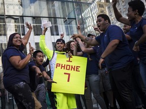 Employees celebrate with a customer as the iPhone 7 smartphone goes on sale outside an Apple Inc. store in New York, U.S., on Friday, Sept. 16, 2016.