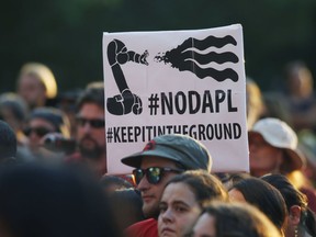 A protester holds up a placard against the construction of the Dakota Access oil pipeline on the Standing Rock Reservation in North Dakota at a unity rally on the west steps of the State Capitol late Thursday, Sept. 8, 2016, in Denver.