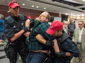 A demonstrator is taken away by police officers after disrupting the National Energy Board public hearing into the proposed $15.7-billion Energy East pipeline in Montreal, before the hearings were halted.