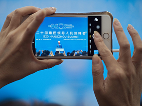 A woman takes a photo with her smartphone of IMF Managing Director Christine Lagarde as she addresses a press conference on the sidelines of the G20 Summit in Hangzhou on Sept. 5, 2016.