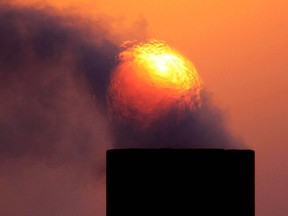 Smoke rises from an oil pipe at sunset in the desert oil field of Sakhir, Bahrain. OPEC nations have agreed in theory that they need to reduce their production to help boost global oil prices.