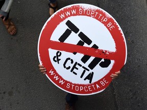 A protestor holds a placard depicting a no entry sign with the TTIP and CETA logos, during a demonstration in Brussels.