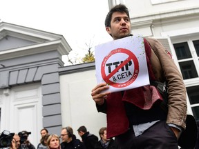 A demonstrator holds a poster reading 'Stop TTIP - Stop CETA' ahead of an emergency meeting of all Belgium federal entities on the EU-Canada Comprehensive Economic and Trade Agreement (CETA) in Brussels on October 24, 2016.