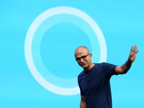 Microsoft CEO Satya Nadella walks in front of the new Cortana logo