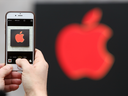 A visitor photographs a red Apple logo with an iPhone at the Apple Store 