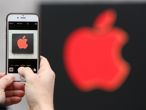 A visitor photographs a red Apple logo with an iPhone at the Apple Store