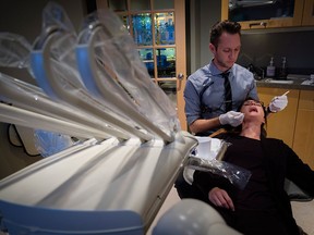 Dr. Kellen Smith examines a patient at his dental practice in Calgary on Nov. 16, 2016.