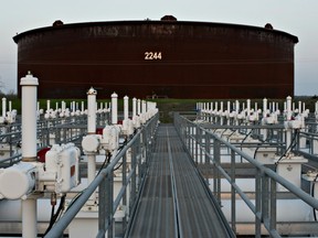 A manifold system, used to direct oil around the facility, stands near crude oil storage tanks in Cushing, Okla.