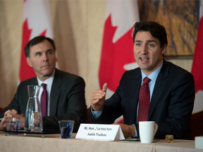 Prime Minister Trudeau (right) takes part in a roundtable in Toronto as Minister of Finance Bill Morneau looks on