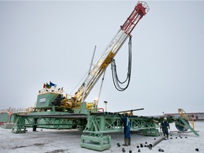 Oil workers remove the caps from a load of drill pipe for a Precision Drilling Trust rig drilling a gas well for Encana Corp.