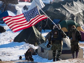 U.S. Navy deep sea diving veteran Rob McHaney (C) holds an American flag as he leads a group of veteran activists back from a police barricade on a bridge near Oceti Sakowin Camp on the edge of the Standing Rock Sioux Reservation on December 4, 2016 outside Cannon Ball, North Dakota.