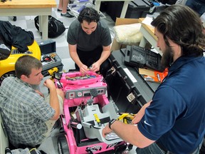 University of North Florida students Garrett Baumann, right, Chris Martin, centre, and Jason Pavichall work to customize a toy car.