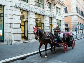 A horse-drawn carriage passes a branch of Banca Monte dei Paschi di Siena SpA bank in Rome.