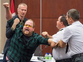 Security guards try to restrain a demonstrator from interrupting the National Energy Board public hearing into the proposed Energy East pipeline project in August before the panel stepped down.