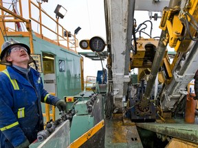 An oilfield services worker operates a drill at an Encana  site.