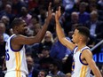 Kevin Durant (left) and Steph Curry of the Golden State Warriors high five during the first half of an NBA game against the Toronto Raptors.