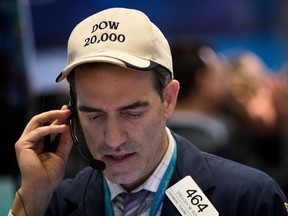 A trader wears a 'Dow 20,000' hat works on the floor of the New York Stock Exchange.