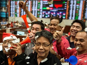 Traders celebrate during the last day of trading in front of a giant electronic board at the Philippine Stock Exchange.