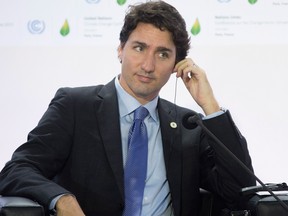 Canadian Prime Minister Justin Trudeau adjusts his translation aid as he listens to speakers during a session on carbon pricing at the United Nations climate change summit on Nov. 30.