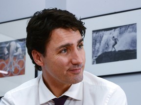 Prime Minister Justin Trudeau takes part in an interview at The Canadian Press bureau in Ottawa on Monday, Dec 19, 2016. A picture of his father Prime Minister Pierre Trudeau in Guyana in 1974 hangs on the wall behind.