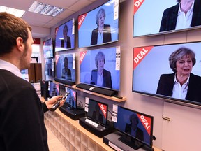 An employee changes the channels of televisions, on display in a store for sale in Liverpool, north-west England, on Tuesday, as they show a live speech by British Prime Minister Theresa May on the government's plans for Brexit.